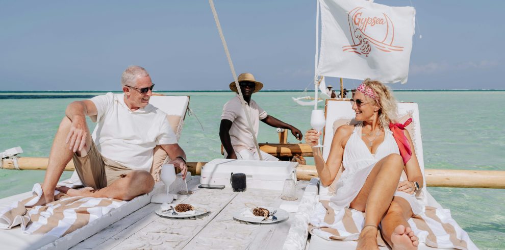 Elderly couple enjoying a luxurious sailboat experience in Zanzibar's turquoise waters.